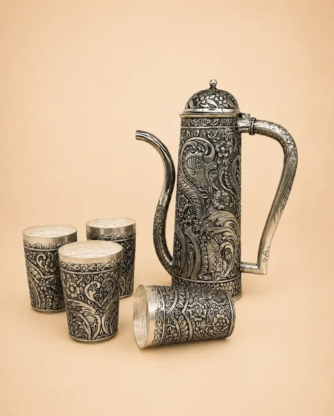 Sterling silver ewer and cups in all-over oxidised floral repoussé, handcrafted in Jaipur.