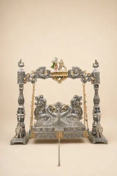 Sterling silver deity swing with a peacock throne and Radha-Krishna figures, handcrafted in Jaipur.